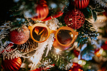  Close-up of a Christmas tree decorated with red ornaments, pinecones, snow-like branches, and...