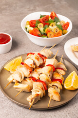 Delicious grilled chicken skewers with capsicum, lemon, salad and ketchup on a plate over the table. Chicken kebab. Healthy food concept.
