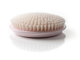 Pink bath brush with soft white bristles resting on white surface