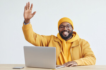 Smiling man in yellow waves sitting at a desk with laptop