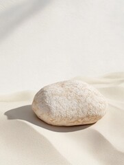 A smooth, pale stone lies peacefully on gentle, undulating sand, embodying serenity and mindfulness amid a backdrop that evokes calmness during Mental Health Awareness Month