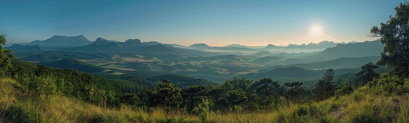 Fototapeta premium Mountains with a sun shining over them and a grassy field