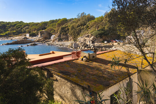 Vista elevada del poblado de pescadores de Cala S'Alger, con techos r&uacute;sticos y costa rocosa.