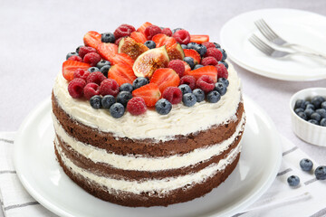 Delicious chocolate sponge cake with berries served on light table, closeup