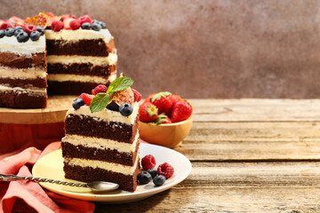 Piece of delicious chocolate sponge cake with berries served on wooden table, space for text