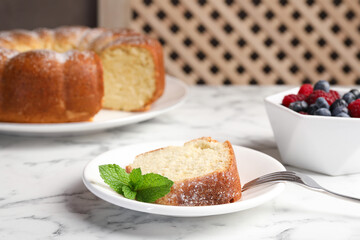Freshly baked sponge cake, mint and berries on white marble table, closeup