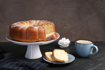 Freshly baked sponge cake, sugar cubes and coffee on black table
