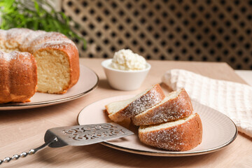 Pieces of freshly baked sponge cake, server and ice cream on wooden table, closeup