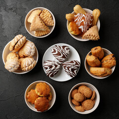 Assorted baked goods arranged in bowls on a dark surface for a festive gathering at a cozy kitchen