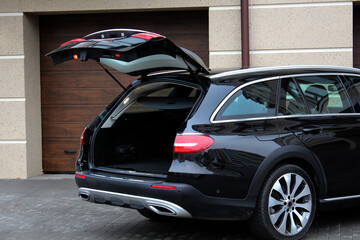 Modern car with open empty trunk outdoors. Black car is ready to load luggage. Clean trunk wagon...