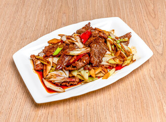 Stir fried beef and welsh onions served in tray dish isolated on wooden table side view of hong kong food