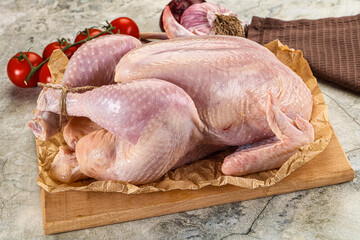 Fresh whole raw chicken over board