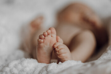 A baby's feet are shown on a white blanket. The baby is sleeping, and the feet are visible in the foreground. Concept of innocence and vulnerability