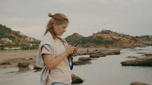 Female tourist shooting panorama video sea beach coastline landscape use smartphone slowmo