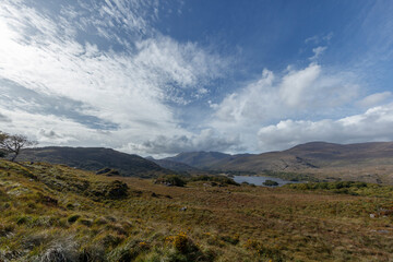 Panoramic view of Irish countryside.  Rolling hills,  lake, and a partly cloudy sky.  Scenic landscape.