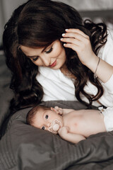 A woman is holding a baby on her lap. The baby is wearing a pacifier