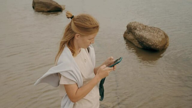Woman tourist use smartphone chatting browsing internet watching photo video sea water beach