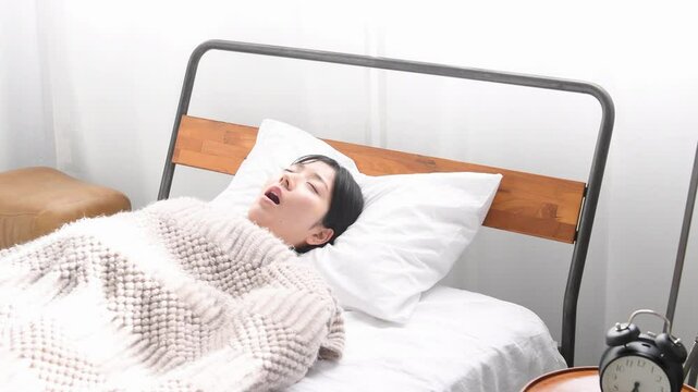 ベッドの上でいびきをかき寝るアジア人女性