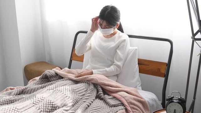 ベッドで咳をする体調不良のアジア人女性