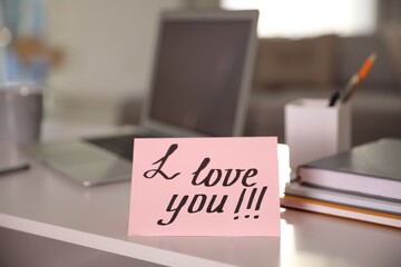 Note with handwritten text I Love You on workplace. Romantic message