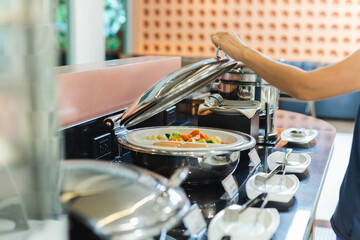 Woman hand taking food in buffet line indoor in hotel