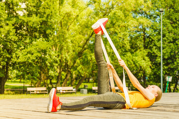Girl doing exercises outdoor, using fit band.