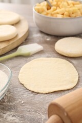 Making pirozhki (stuffed pastry pies). Pieces of dough on wooden table, closeup