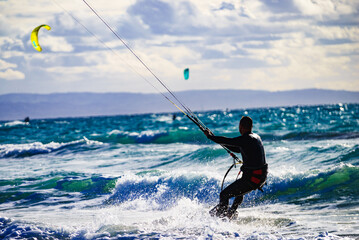 Kite surfer riding waves. Kiteboarding sport.