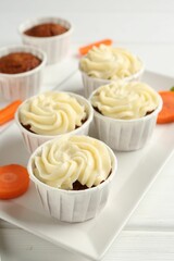 Delicious carrot muffins and fresh vegetable on white wooden table, closeup