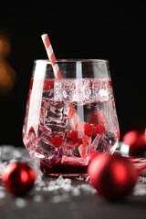 Tasty Christmas cocktail in glass, ice and decor on table, closeup