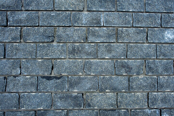 Obraz premium Wall of stones. Brick wall. Gray background with black geometric patterns, of rectangular stones, bricks. Part of a stone wall pattern for background, texture or text. rough grainy stone wall
