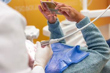 Patient holding mirror while dentist performing dental checkup