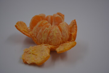 Healthy, healthy food, groceries, fresh fruits. Many orange tangerine slices with peeled orange tangerine peel are located on a white plastic background.