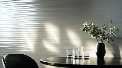 A modern table setting with glasses and a plant against a textured wall.