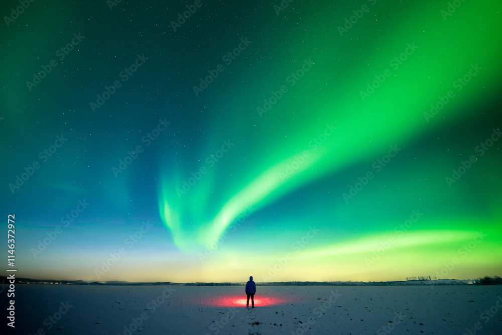 Wall mural man with red flashlight standing on snowy field against the backdrop of incredible starry sky with a