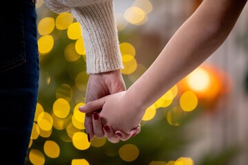 A loving couple is holding hands amidst the beautiful lights that illuminate the background