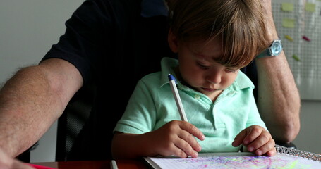 Naklejka premium Multi-tasking grand-father working while taking care of toddler boy while he doodles