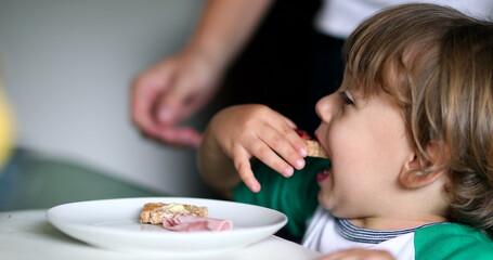 Toddler baby boy eating breakfast toast with jelly in the morning