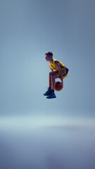 Dynamic image of little boy dressed basketball uniform, playing basketball and ready to get...