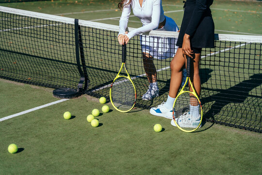 Two multiethnic friends female tennis players in black and white sport wears.