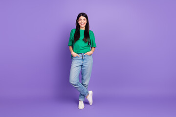 Young woman in casual green t-shirt posing confidently on vibrant purple backdrop, exuding joy and charm