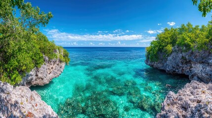 Fototapeta premium Idyllic turquoise cove with rocky shores and lush greenery under a vibrant blue sky.