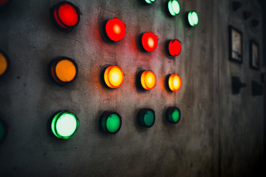 Array of red, green and yellow industrial signal lamp indicators on old and rustic electrical power control center panel