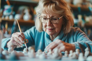 Senior woman painting delicate ceramic figurines as a peaceful pastime.