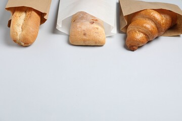 Paper bags with fresh pastries on white background, space for text