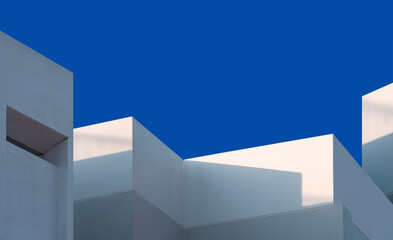 Geometric exterior architecture in minimal style, Modern house Building with light and shadow on white and gray concrete wall surface against blue clear sky background, Perspective low angle view 