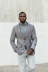 Obraz premium Portrait of an elegant and handsome black businessman wearing gray suit in a concrete wall in the city