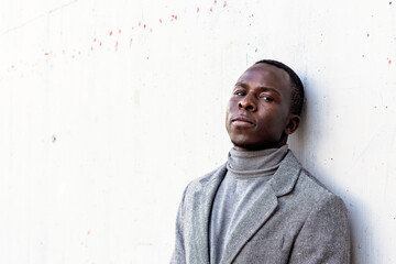 Portrait of an elegant and handsome black businessman wearing gray suit in a concrete wall in the city