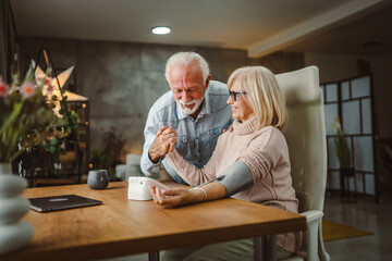 senior man support and help his senior wife to measure blood pressure