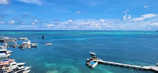 A breath-taking view of a tropical beach with crystal-clear turquoise water, boats docked at a...